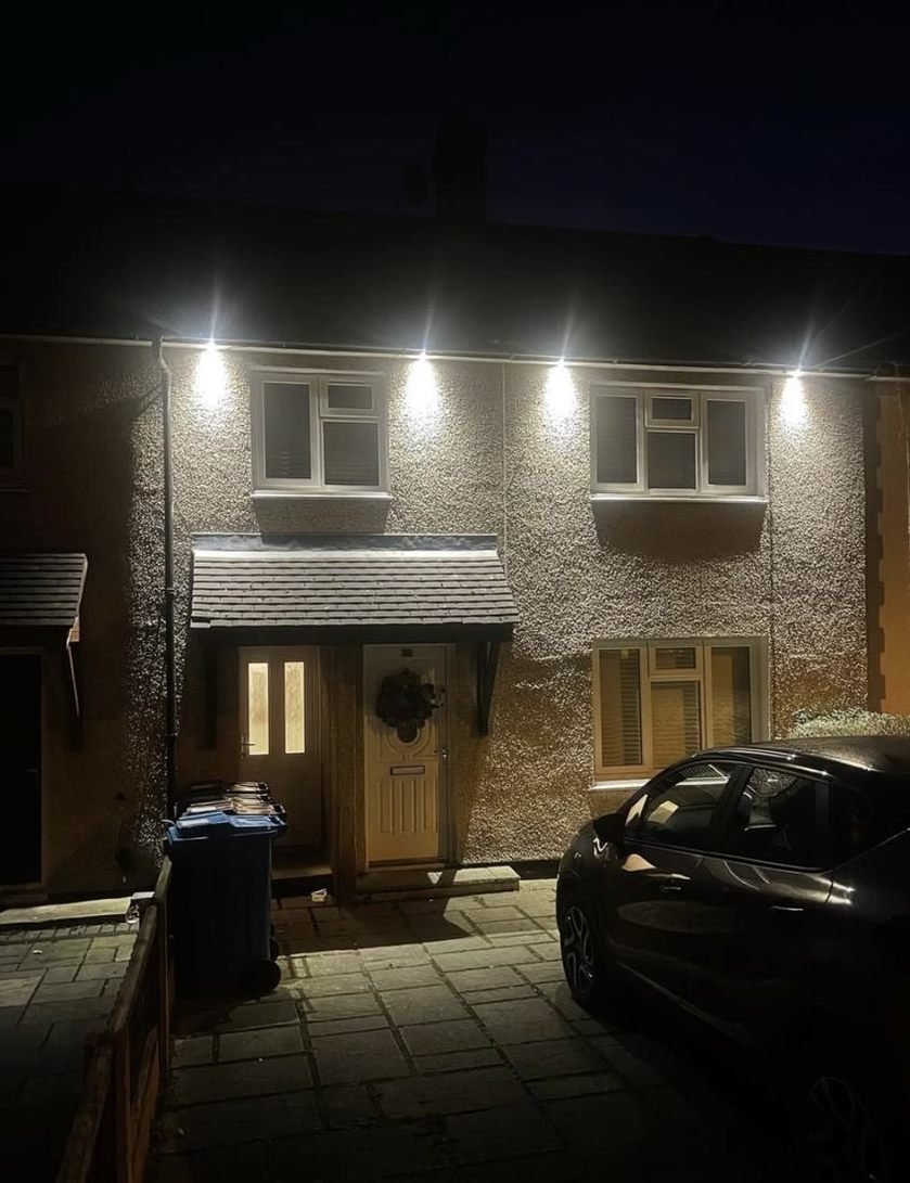 Terraced house front lit at night by soffit downlights